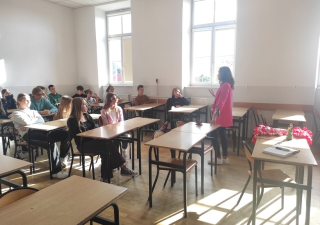 Nauczycielka prowadzi zajęcia z języka hiszpańskiego przed grupą uczniów siedzących w ławkach